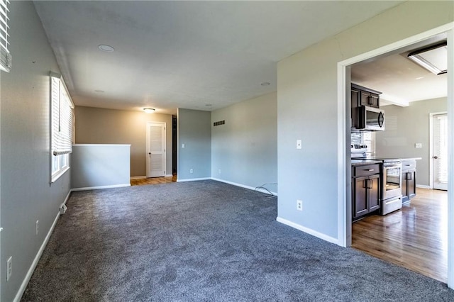 unfurnished room with dark colored carpet, visible vents, and baseboards