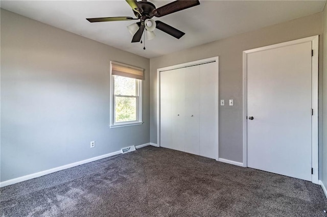 unfurnished bedroom featuring a closet, dark carpet, and baseboards