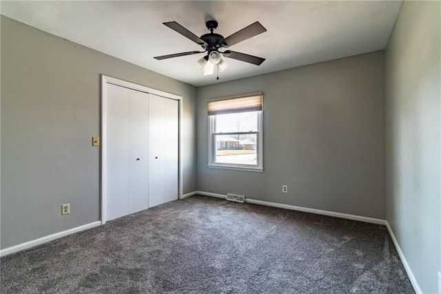 unfurnished bedroom featuring dark colored carpet, a closet, visible vents, and baseboards