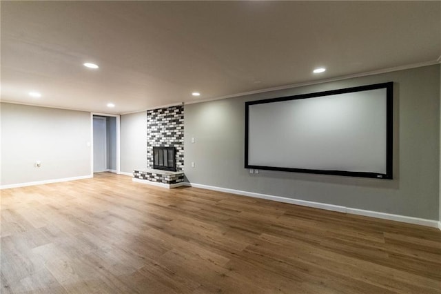 cinema room featuring a large fireplace, baseboards, ornamental molding, and wood finished floors