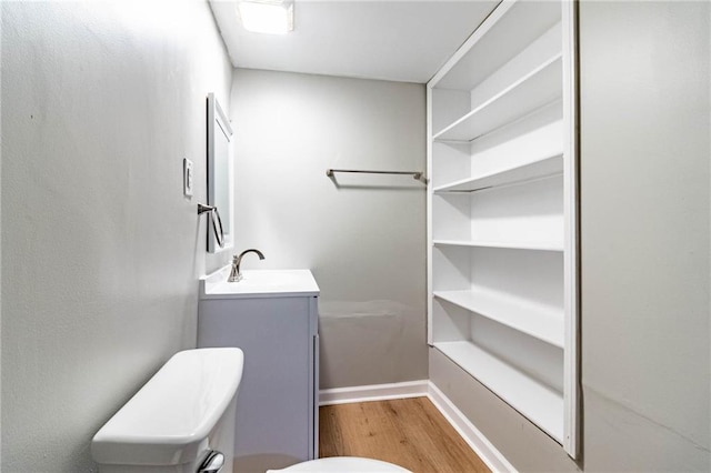 bathroom featuring toilet, baseboards, wood finished floors, and vanity