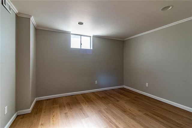 spare room with baseboards, visible vents, ornamental molding, and wood finished floors