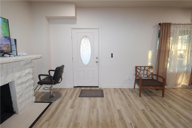 foyer with a fireplace, baseboards, and wood finished floors