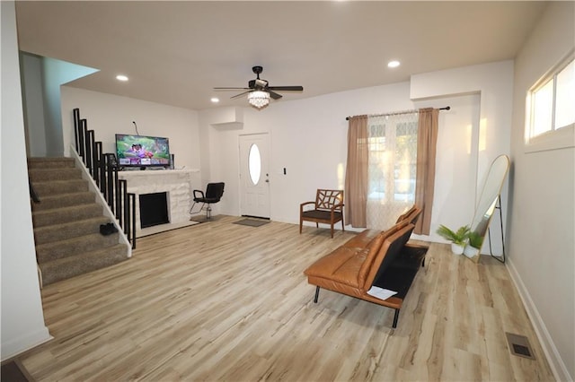 sitting room featuring light wood-style flooring, recessed lighting, a fireplace with flush hearth, visible vents, and stairs