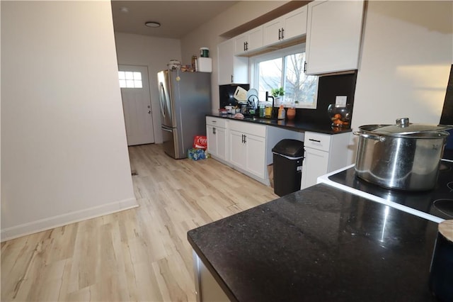 kitchen featuring white cabinets, a wealth of natural light, and freestanding refrigerator