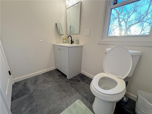 bathroom with baseboards, vanity, and toilet