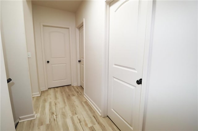 corridor with light wood-style floors and baseboards