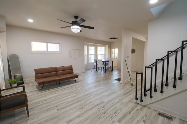 living area featuring light wood-style flooring, recessed lighting, visible vents, baseboards, and stairway