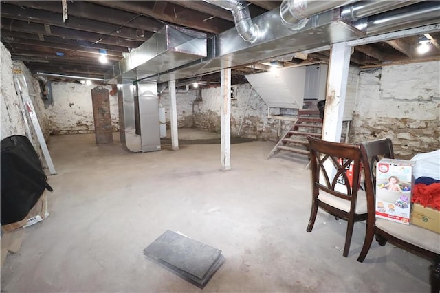 unfinished basement featuring stairway and heating unit