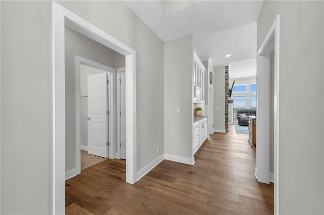 corridor with recessed lighting, wood finished floors, and baseboards