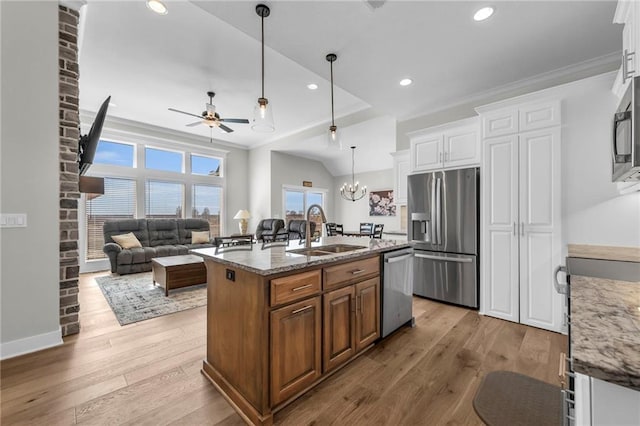 kitchen with a sink, light stone counters, wood finished floors, appliances with stainless steel finishes, and crown molding