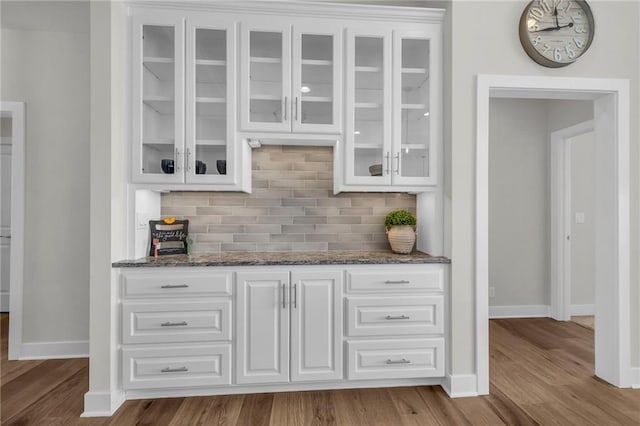 bar with baseboards, backsplash, and wood finished floors