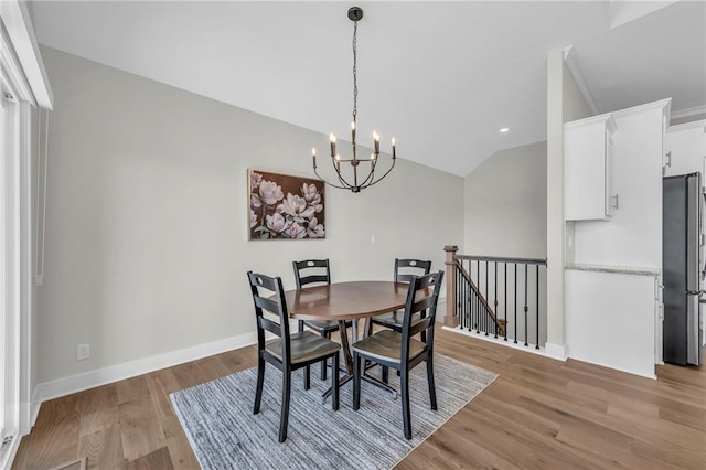 dining area featuring lofted ceiling, light wood-style flooring, baseboards, and a chandelier