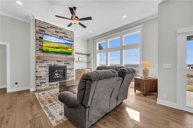 living room featuring baseboards, wood finished floors, ceiling fan, and crown molding