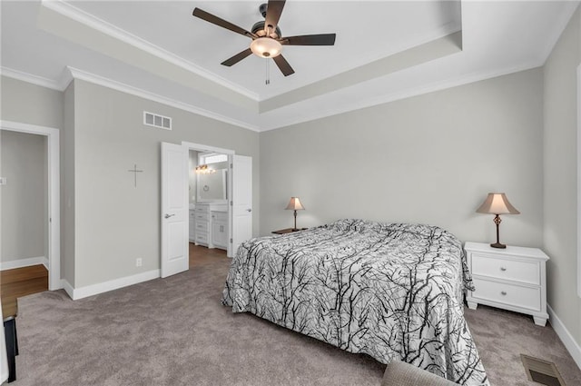 carpeted bedroom featuring a raised ceiling, baseboards, visible vents, and ornamental molding