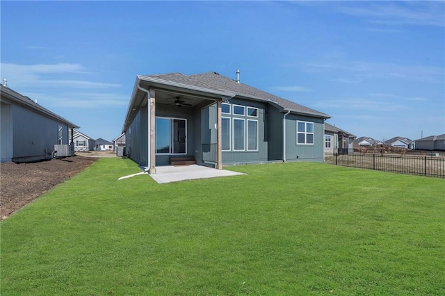 rear view of property featuring a patio, a lawn, ceiling fan, and fence