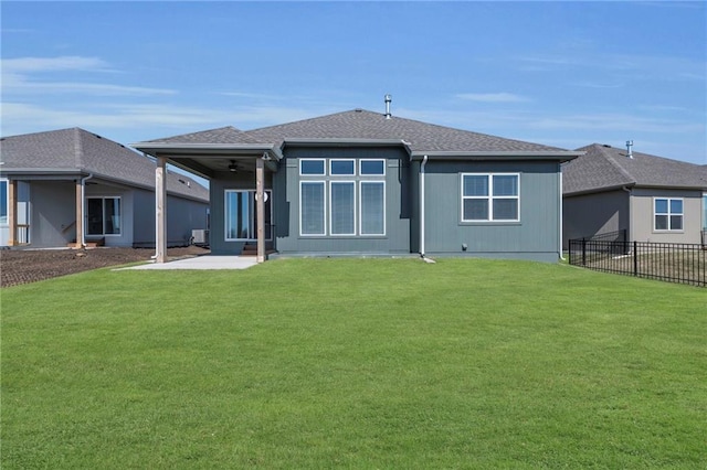 rear view of house with a patio area, a yard, fence, and roof with shingles