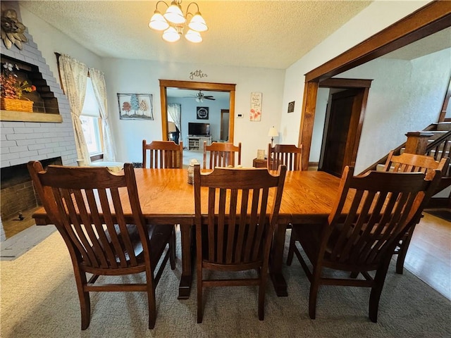 carpeted dining space featuring an inviting chandelier, a brick fireplace, and a textured ceiling