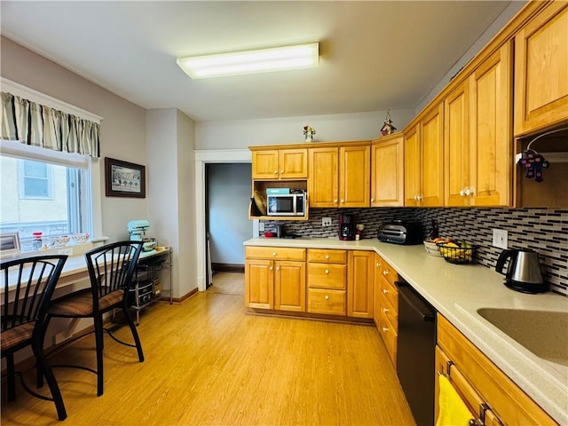 kitchen featuring light wood finished floors, light countertops, black dishwasher, stainless steel microwave, and backsplash