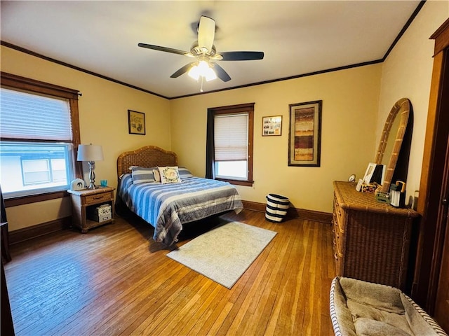 bedroom featuring ceiling fan, light wood-style flooring, baseboards, and ornamental molding