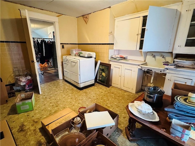 kitchen featuring a wainscoted wall, a sink, washer / clothes dryer, tile walls, and light countertops