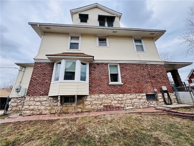 rear view of property featuring a gate, a yard, fence, and brick siding