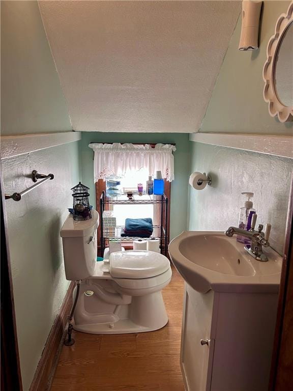 bathroom featuring a textured ceiling, toilet, vanity, and wood finished floors