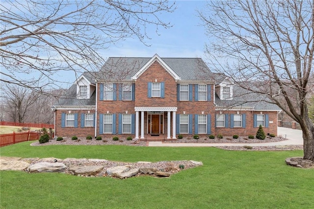 view of front of home with a front yard, fence, and brick siding