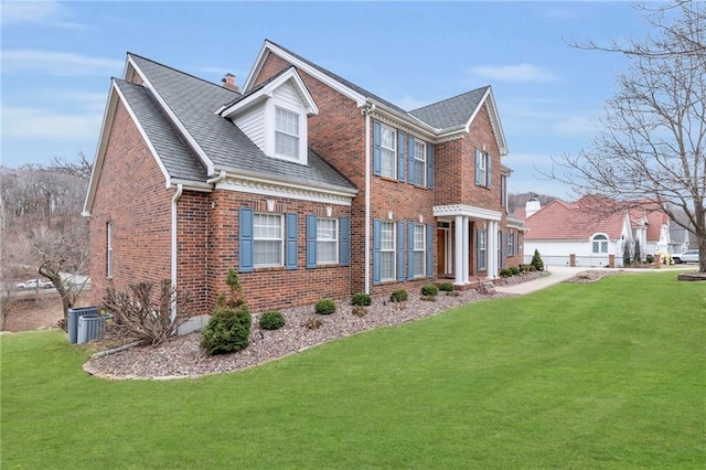 view of front of property featuring brick siding, central AC unit, a front yard, and roof with shingles