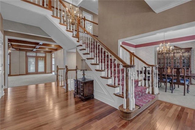 stairway featuring ornamental molding, beam ceiling, an inviting chandelier, wood finished floors, and coffered ceiling