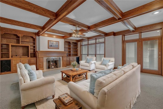 carpeted living room with built in shelves, ceiling fan, beam ceiling, a fireplace, and coffered ceiling