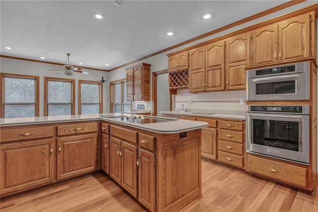 kitchen featuring light countertops, ornamental molding, light wood-style flooring, stainless steel double oven, and black electric cooktop