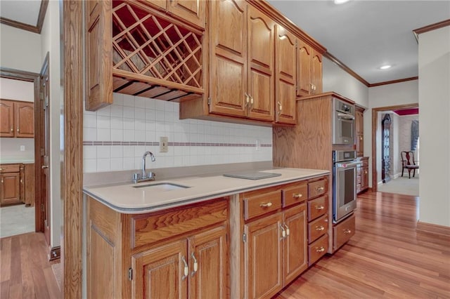 kitchen featuring light wood-style flooring, ornamental molding, a sink, backsplash, and light countertops