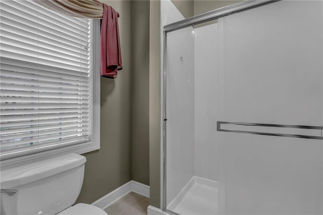 bathroom featuring a shower stall, toilet, baseboards, and tile patterned floors