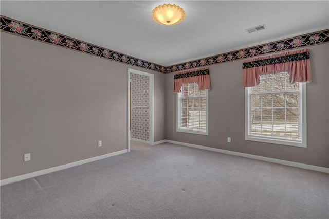 carpeted spare room featuring visible vents and baseboards