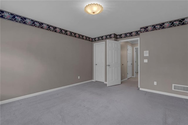 empty room featuring visible vents, baseboards, and carpet flooring