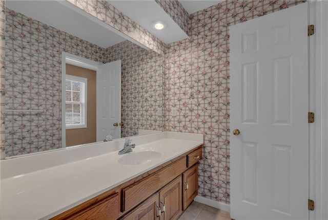 bathroom with baseboards, vanity, tile patterned flooring, and wallpapered walls