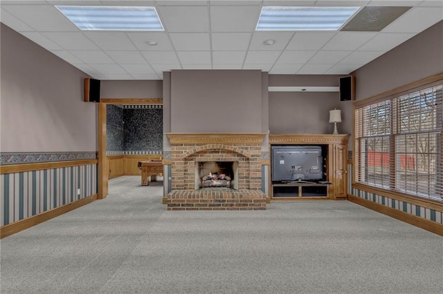 unfurnished living room featuring a wainscoted wall, a paneled ceiling, carpet flooring, and a fireplace