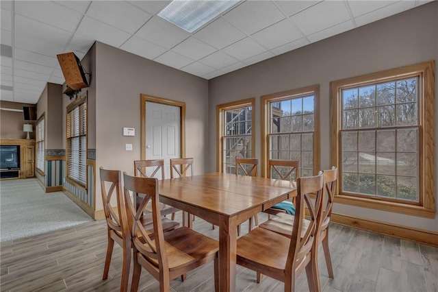 dining space featuring wood finished floors, baseboards, and a drop ceiling