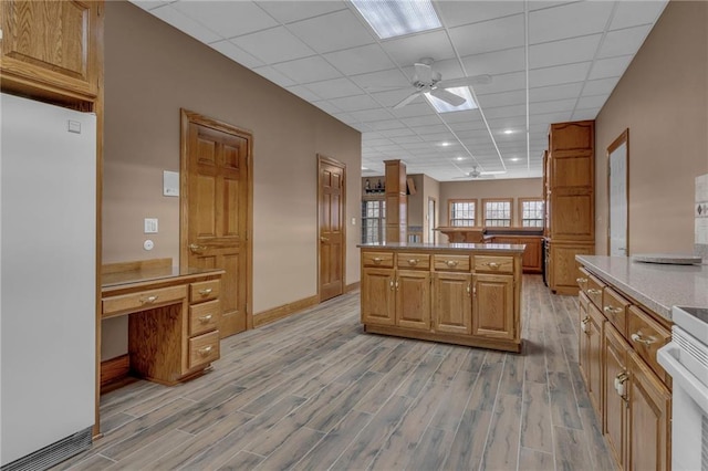 kitchen featuring light wood-style flooring, refrigerator, a center island, and ceiling fan