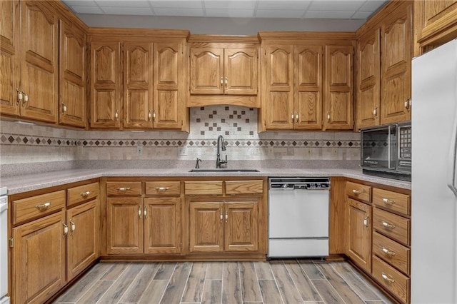 kitchen with white appliances, light countertops, light wood finished floors, and a sink