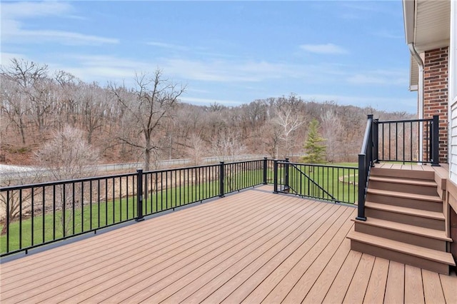 wooden terrace featuring a yard, a view of trees, and fence