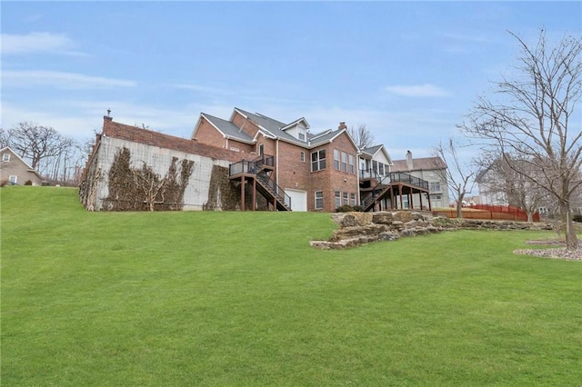 rear view of property featuring a lawn, a deck, and stairs