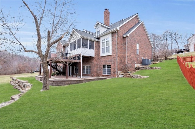 back of property with brick siding, a chimney, a yard, a sunroom, and a patio area