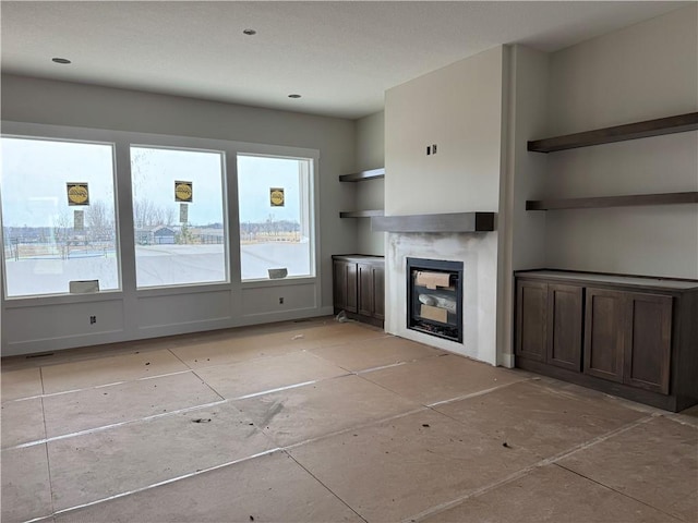 unfurnished living room with a glass covered fireplace and visible vents