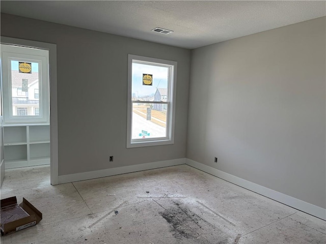 empty room featuring visible vents, a healthy amount of sunlight, and baseboards