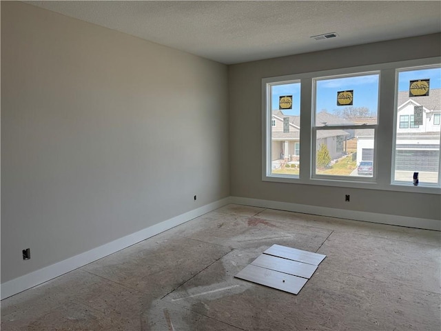 unfurnished room with visible vents, baseboards, and a textured ceiling