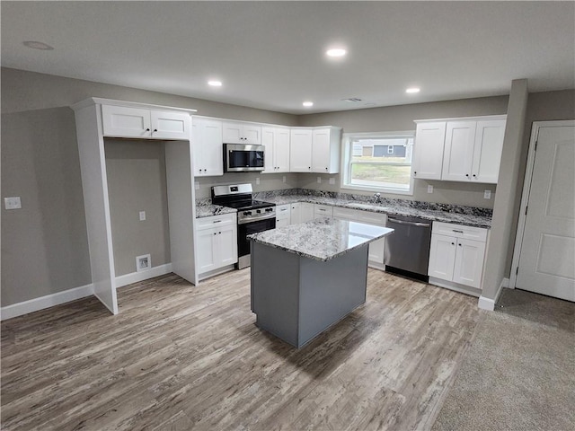 kitchen with light wood-style flooring, appliances with stainless steel finishes, white cabinets, and a sink