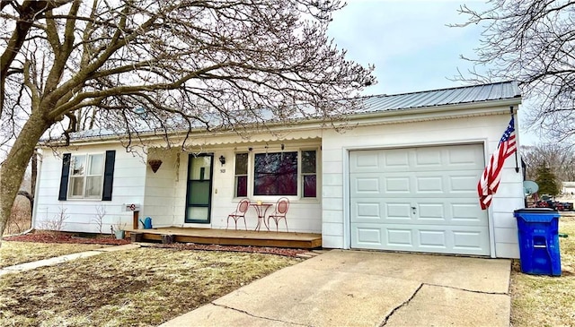 ranch-style house featuring an attached garage, covered porch, metal roof, and concrete driveway