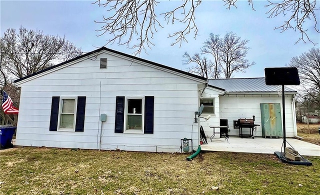 back of house featuring metal roof, a patio, and a lawn